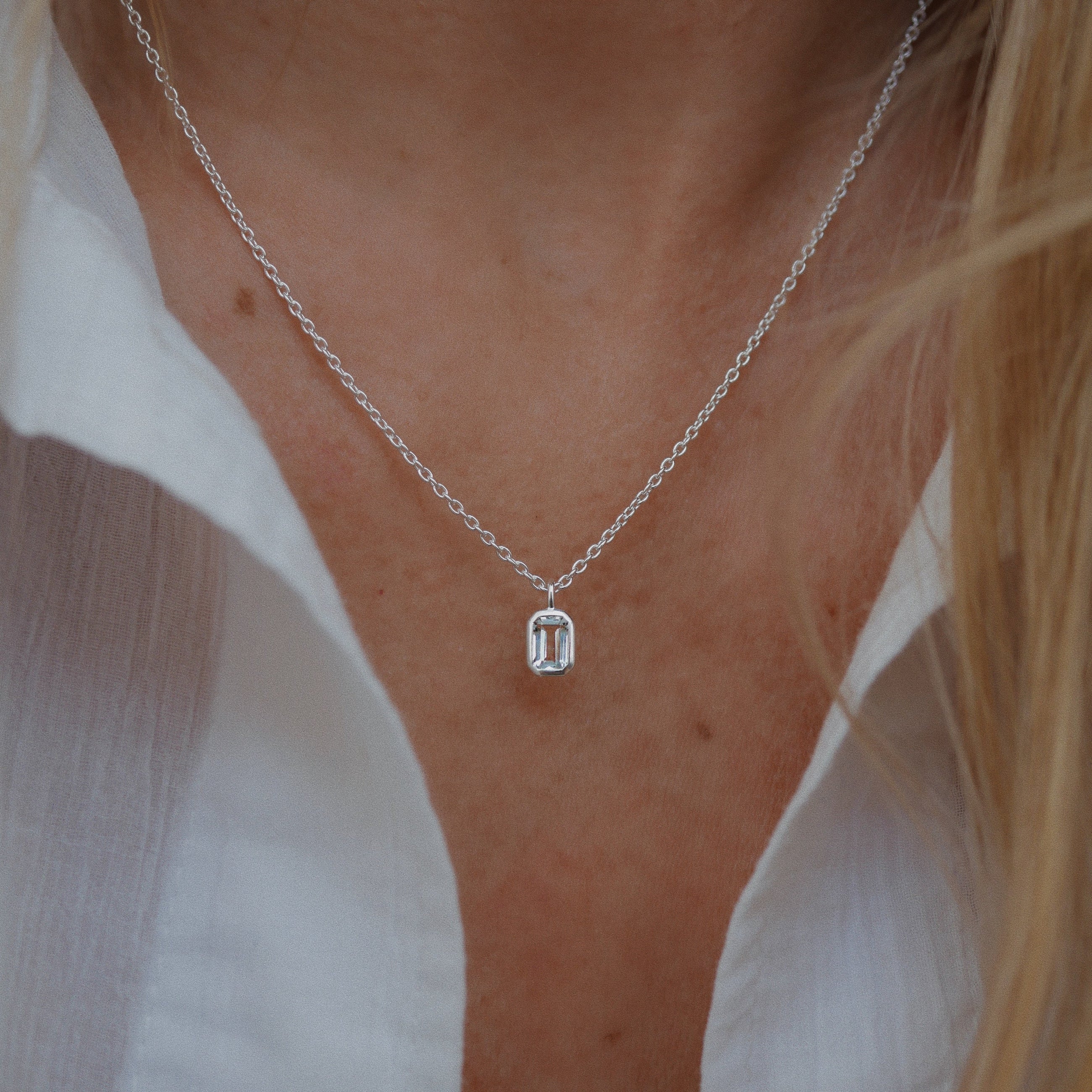 Silver necklace with a pendant worn by a person