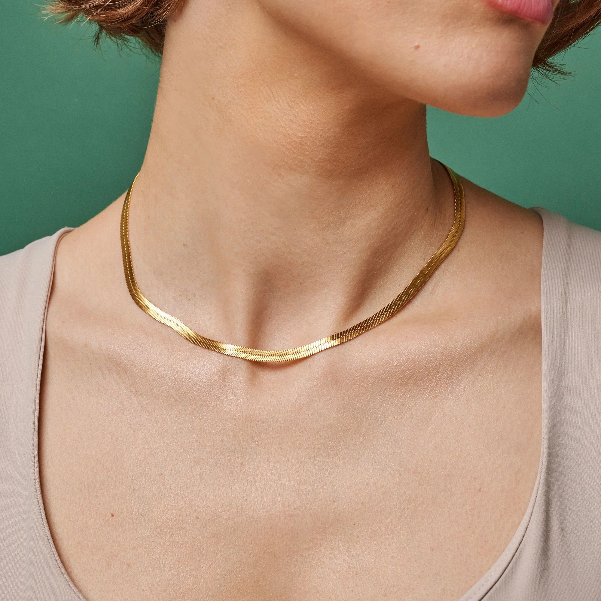 Gold necklace on a person against a green background