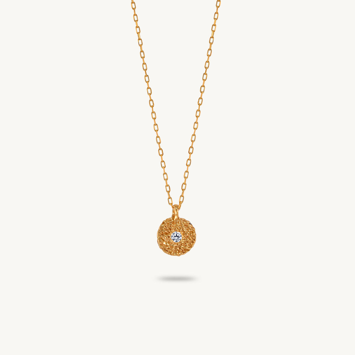 Gold-plated silver chain necklace featuring a round, textured disc pendant with a small white sapphire set in the center.