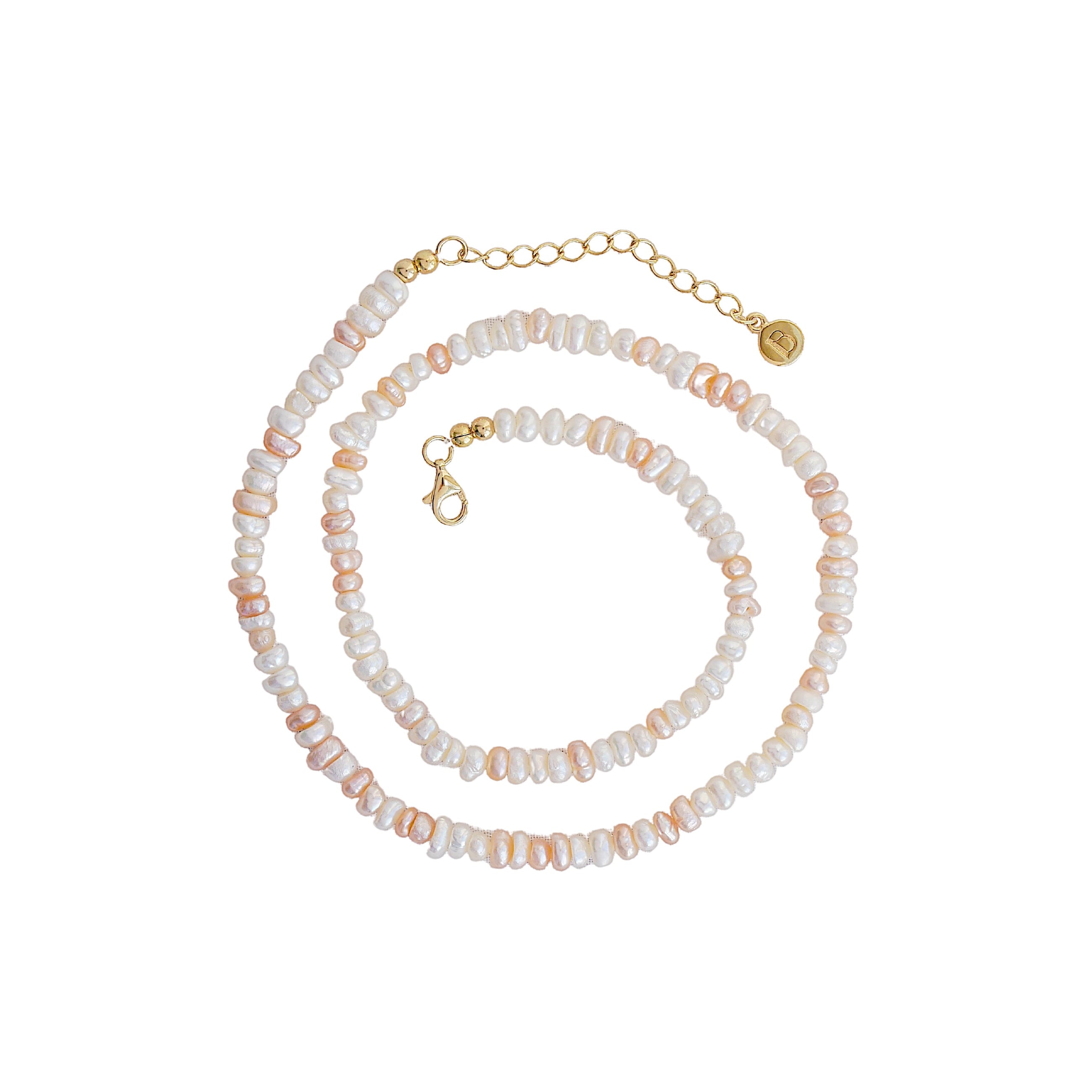 A beaded necklace featuring white and pale pink baroque pearls threaded with small gold-toned beads, finished with a gold lobster clasp, extender chain, and round brand tag.