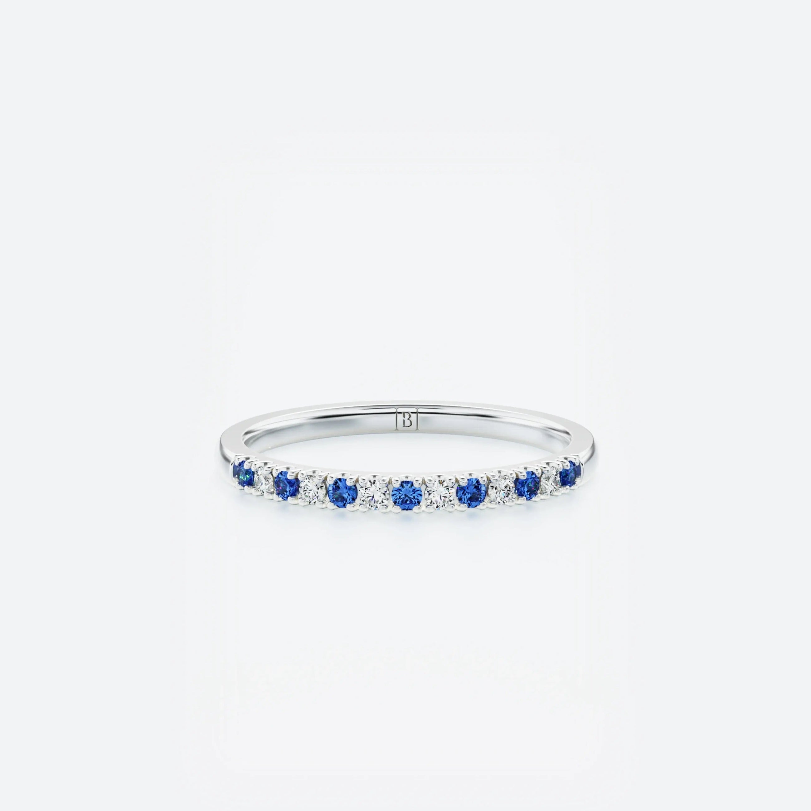 White gold ring with small diamonds & blue sapphires on a white background