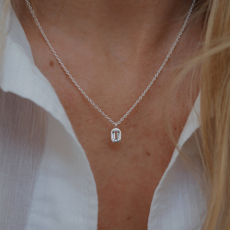 Silver necklace with a pendant worn by a person