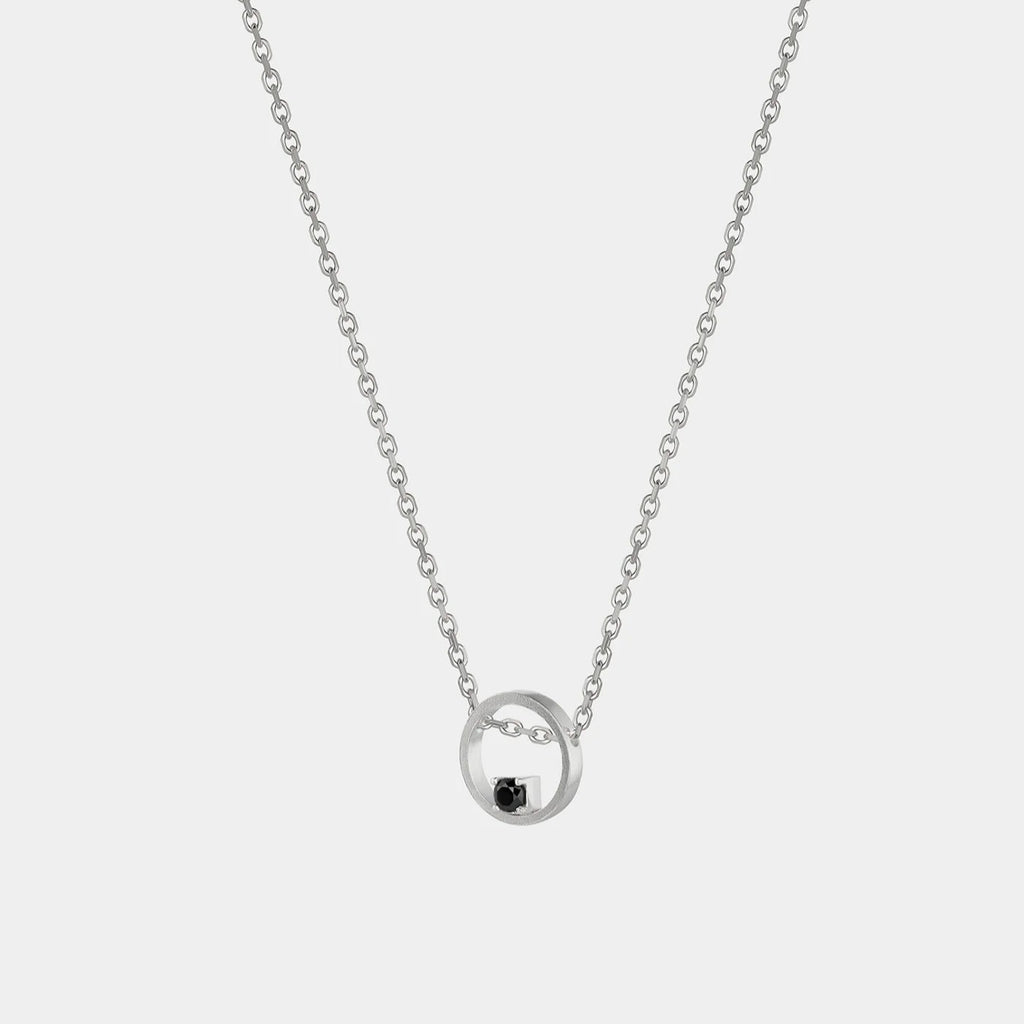 Silver necklace with a small black pendant on a white background