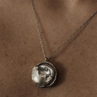 Silver necklace with a textured pendant on a brown background