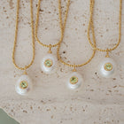Three pearl necklaces with green gemstones on a textured beige surface