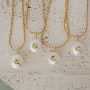 Three pearl necklaces with green gemstones on a textured beige surface
