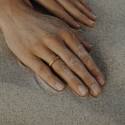 Hand wearing a single 24k gold hand-forged seamless ring on a white background