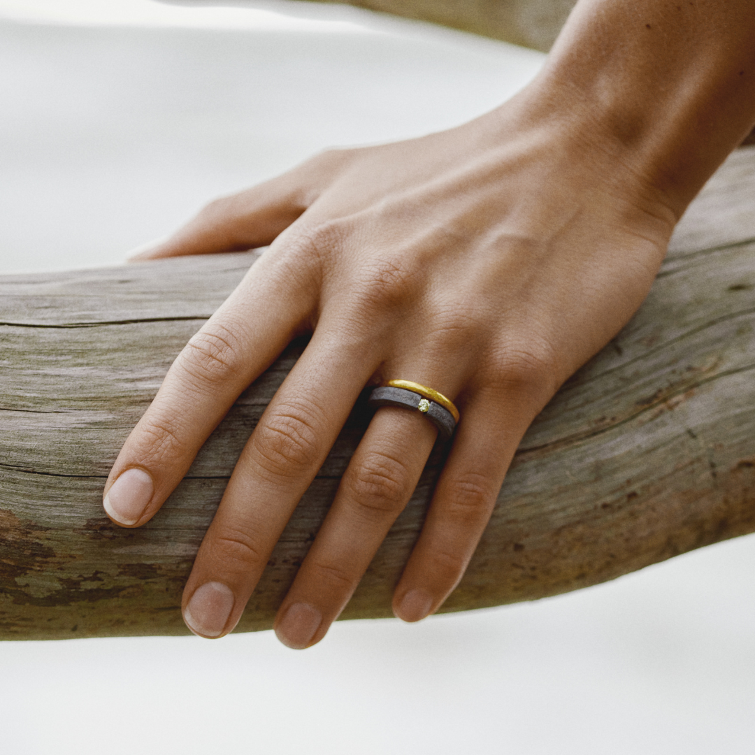 Hand wearing a single 24k gold hand-forged seamless ring on a white background