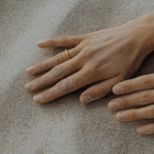 Hand wearing a single 24k gold hand-forged seamless ring on a white background