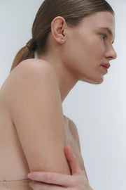Woman with a ponytail and wearing minimal design yellow gold and freshwater pearl stud earring by Adele Notes.