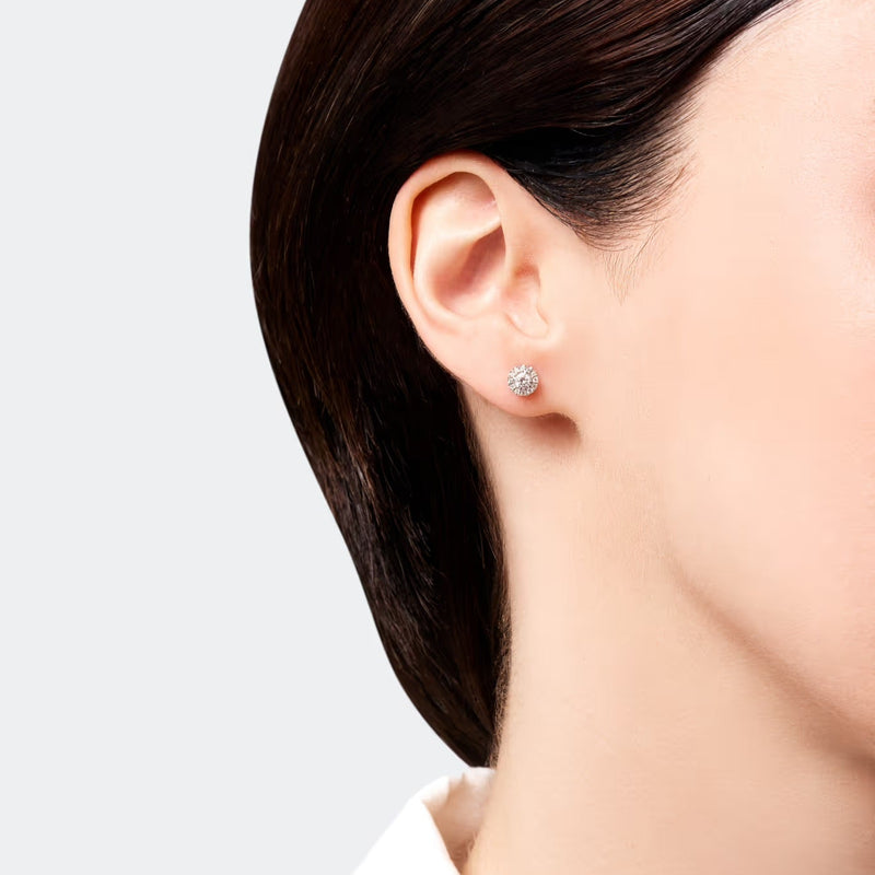 Woman wearing halo stud diamond earrings in 14k gold featuring a central diamond surrounded by a delicate halo of pavé-set diamonds, with a total carat weight of 0.30 ct.