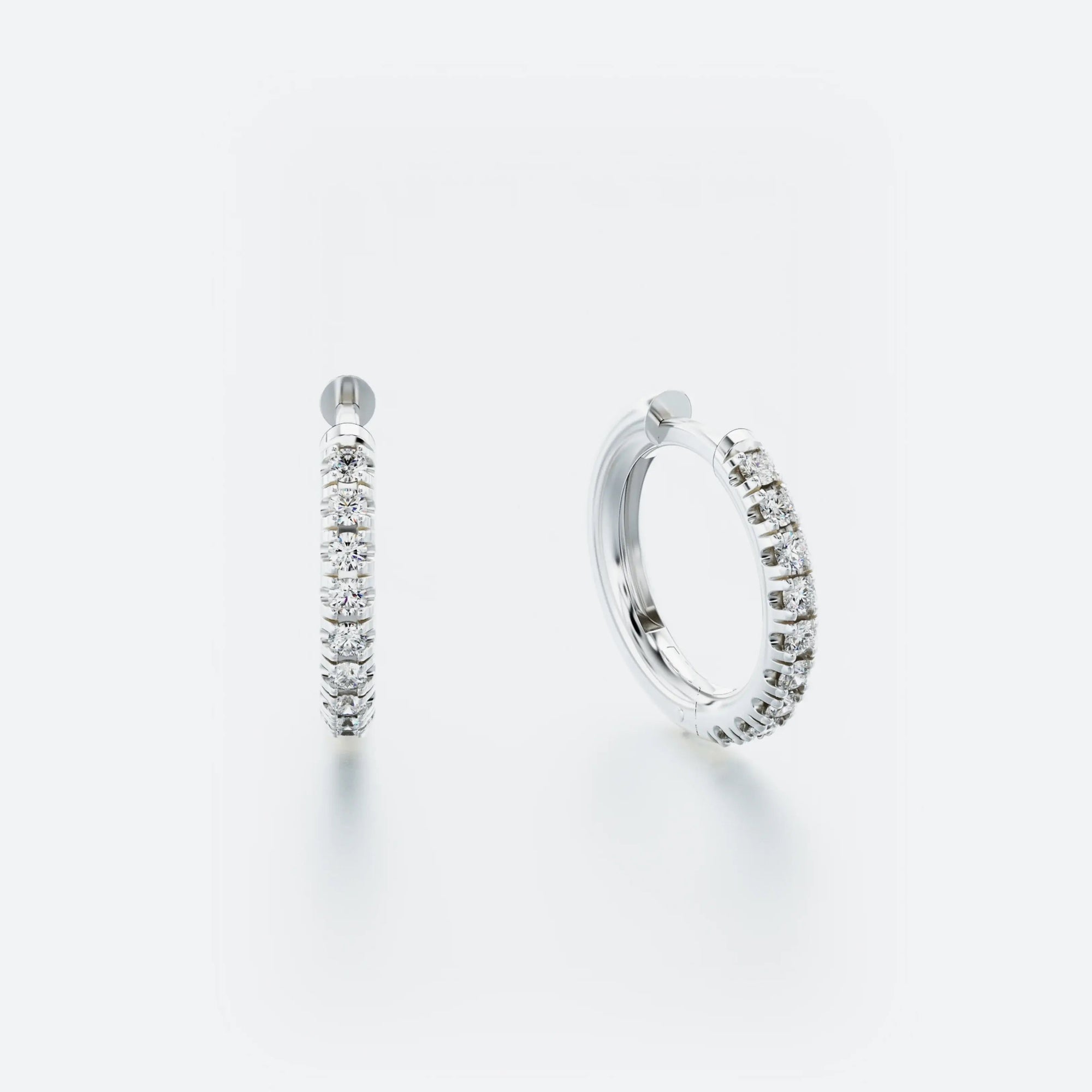A pair of white gold hoop earrings with pavé-set diamonds around the hoop.
