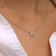 Woman wearing a delicate flower pendant crafted in 14k white gold, adorned with marquise-cut diamonds.