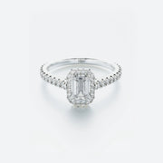 Diamond ring with emerald-cut center stone on a light gray background
