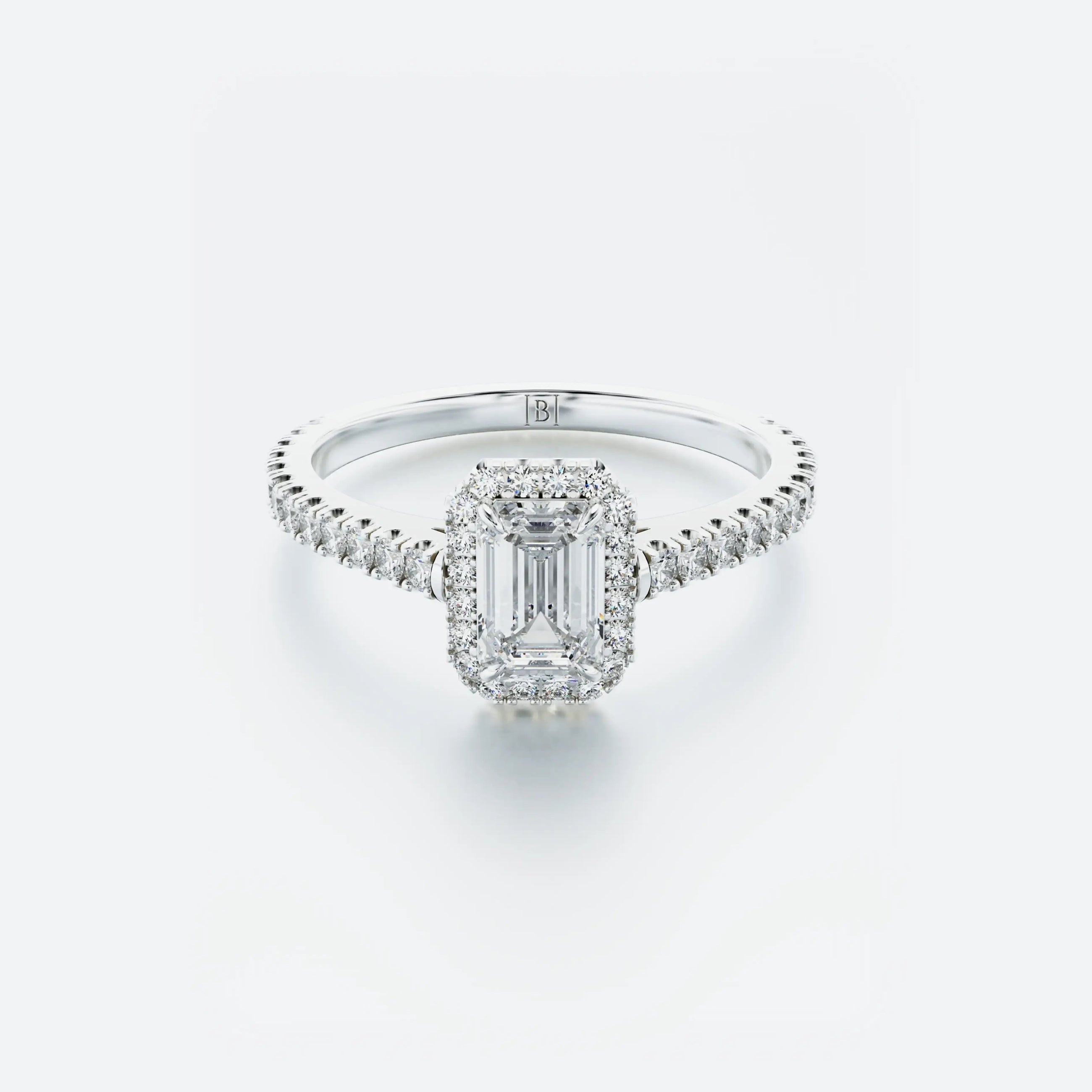 Diamond ring with emerald-cut center stone on a light gray background