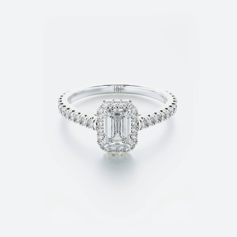 Diamond ring with emerald-cut center stone on a light gray background