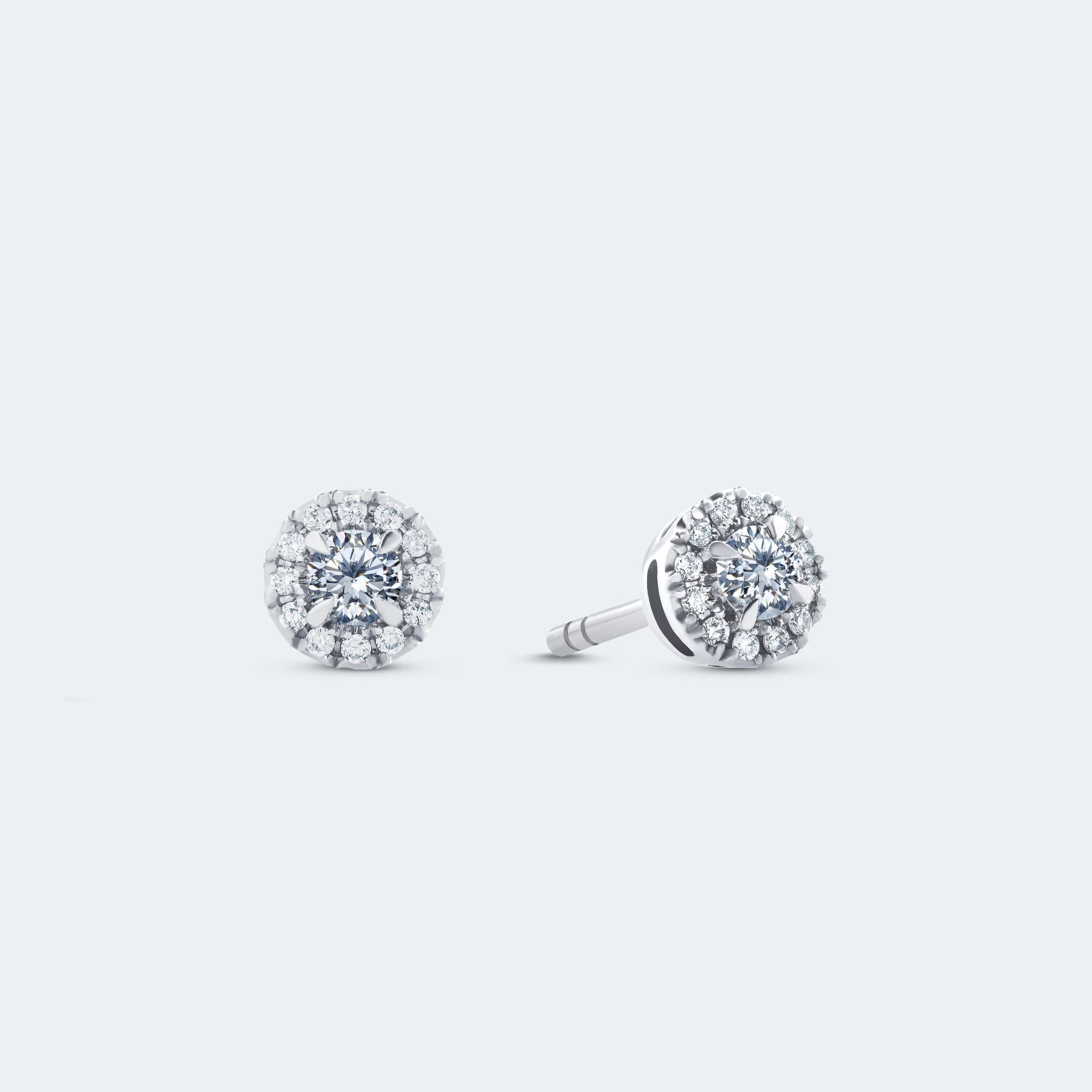 A pair of 14k white gold halo stud diamond earrings with a central diamond surrounded by a halo of pavé-set diamonds.