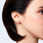 Woman wearing a round brilliant-cut diamond stud earring in white gold.