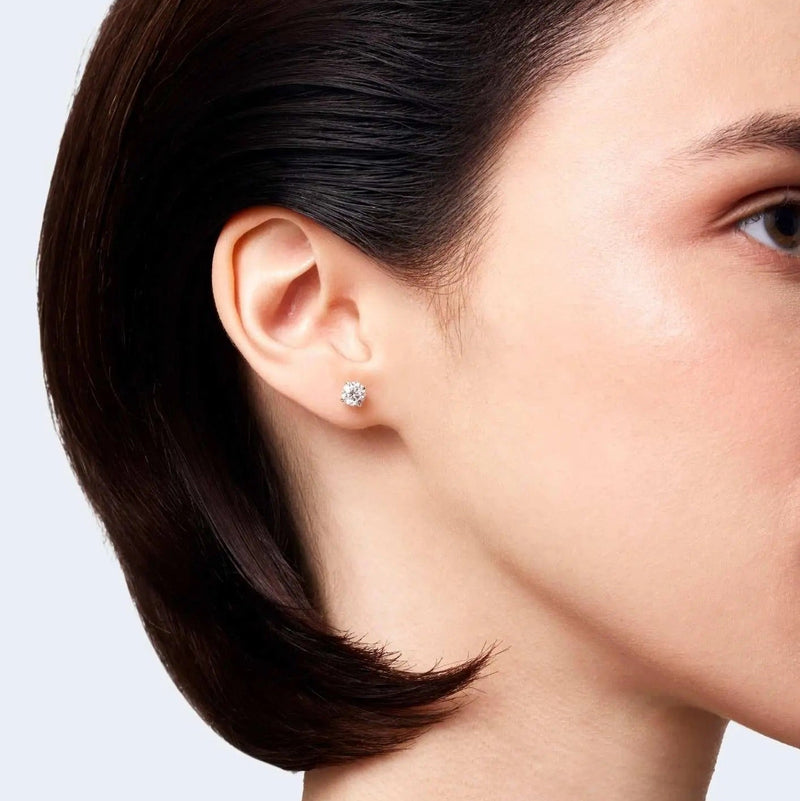 Woman wearing a round brilliant-cut diamond stud earring in white gold.