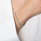 Person wearing tennis bracelet created in 14k white gold, featuring a seamless row of brilliant diamonds set along the entire band for a continuous sparkle. 