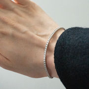 Person wearing tennis bracelet created in 14k white gold, featuring a seamless row of brilliant diamonds set along the entire band for a continuous sparkle. 