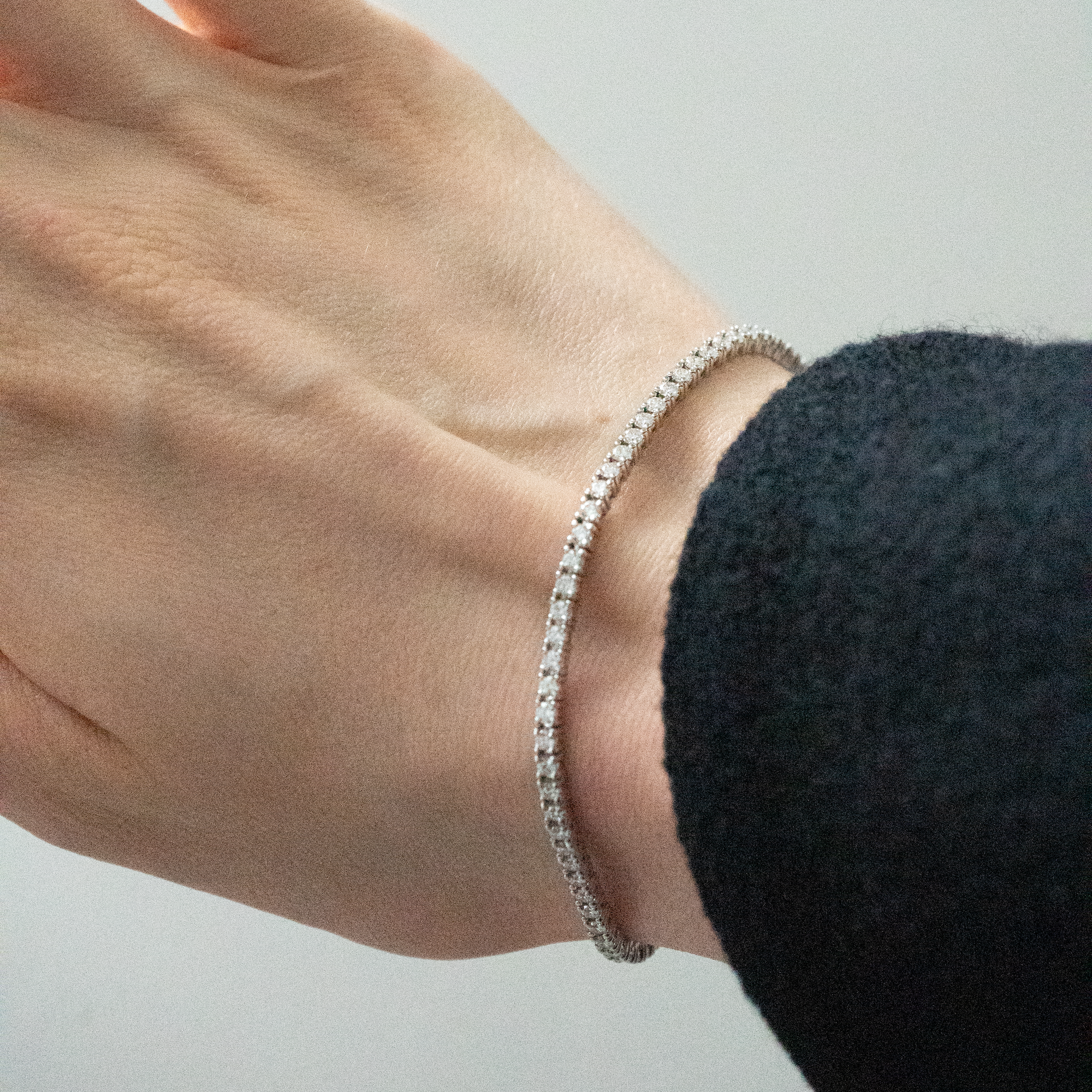 Person wearing tennis bracelet created in 14k white gold, featuring a seamless row of brilliant diamonds set along the entire band for a continuous sparkle. 