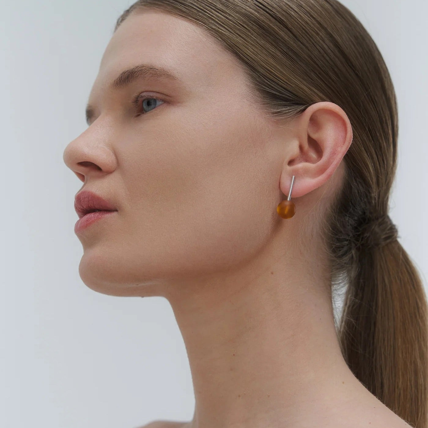 earrings, featuring a structured band and a bold Baltic amber element.