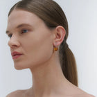 earrings, featuring a structured band and a bold Baltic amber element.