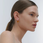earrings, featuring a structured band and a bold Baltic amber element.