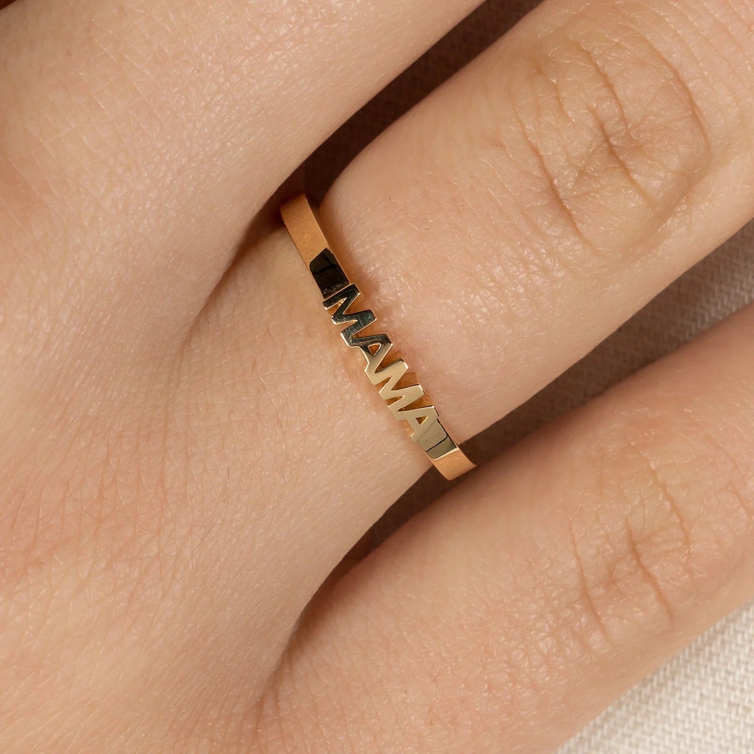 Gold ring with 'MAMA' engraving on a finger