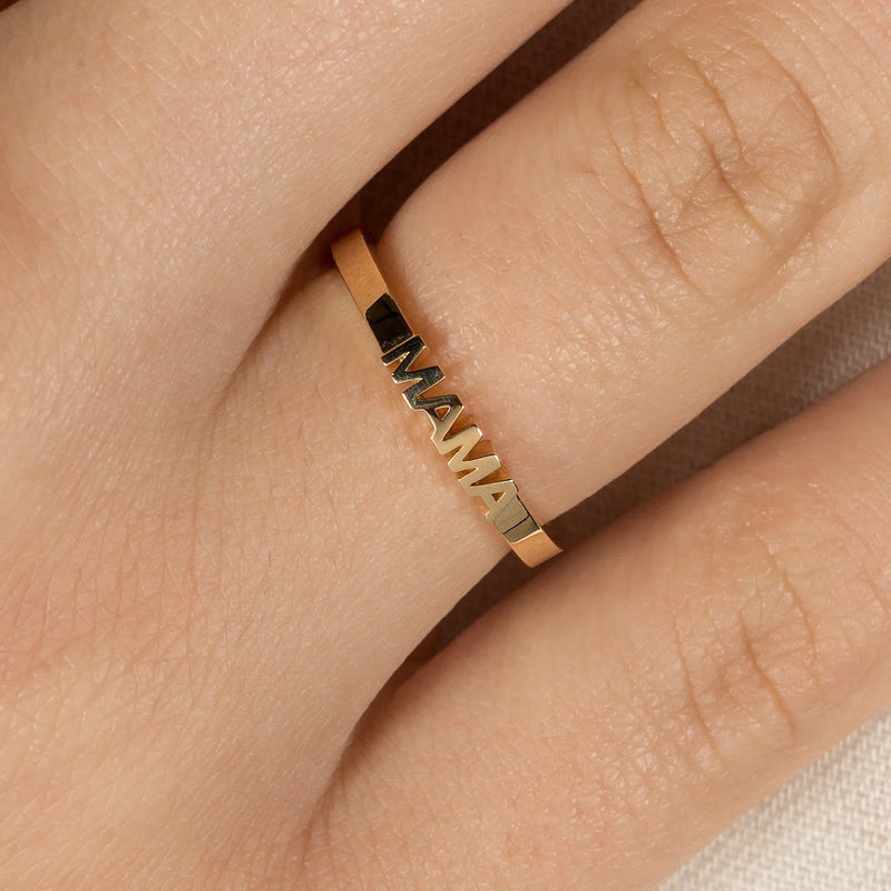 Gold ring with 'MAMA' engraving on a finger