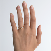 Hand wearing two gold and diamond rings titled "Boy" and "Girl".