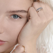 Woman wearing two gold rings with word Mama set with single diamond.