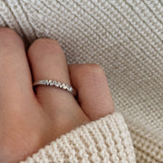 Hand wearing white gold ring with word Mama set with single diamond.