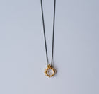 Gold necklace with a unique pendant on a light gray background