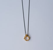 Gold necklace with a unique pendant on a light gray background