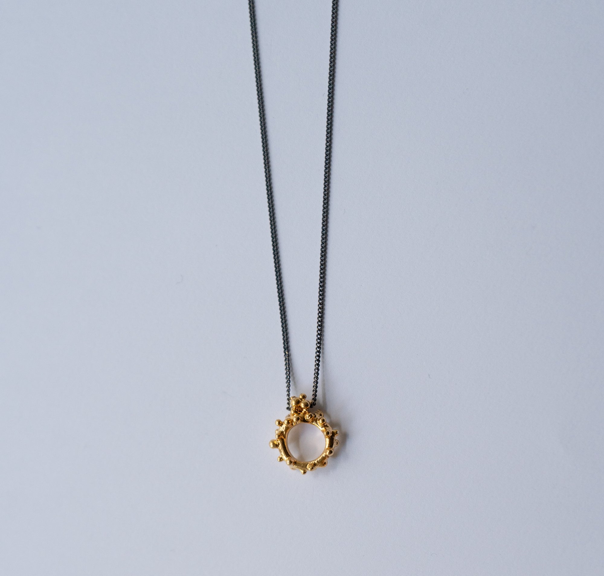 Gold necklace with a unique pendant on a light gray background