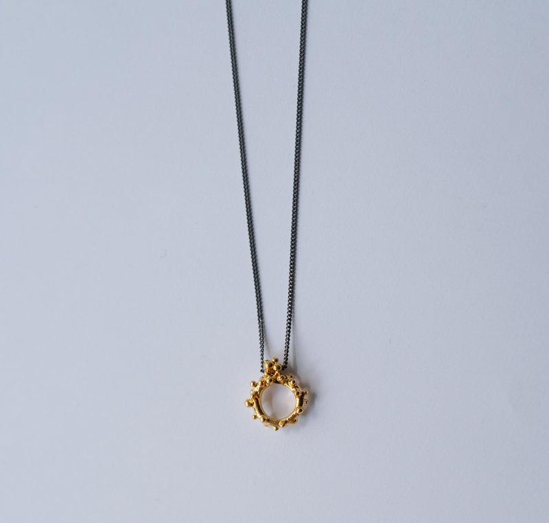 Gold necklace with a unique pendant on a light gray background