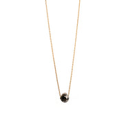 A delicate gold necklace with a faceted diamond pendant, displayed on a clean white background.