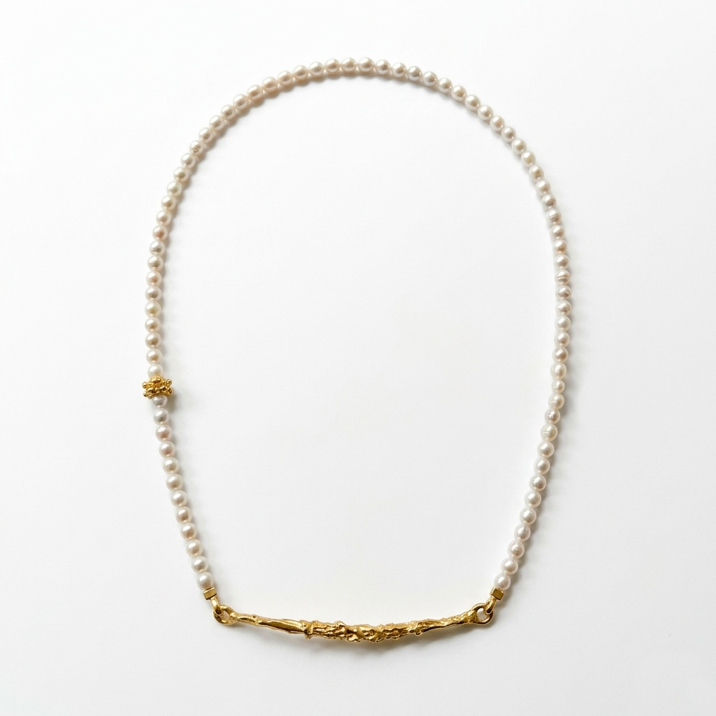 Pearl necklace with gold accents on a white background