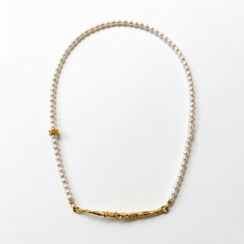 Pearl necklace with gold accents on a white background