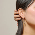 Close-up of a person wearing a silver earring with a neutral background