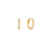 A pair of small gold-plated silver huggie hoop earrings, shown from the side and back, each adorned with five clear round-cut topaz gemstones in a bezel setting, on a solid white background.