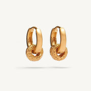 A pair of gold huggie hoop earrings with a textured, chain-link style lower section, shown on a clean off-white background.