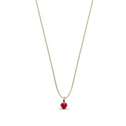 A delicate gold chain necklace featuring a small, polished red heart pendant, presented on a clean white background.