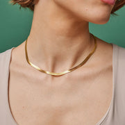 Gold necklace on a person against a green background