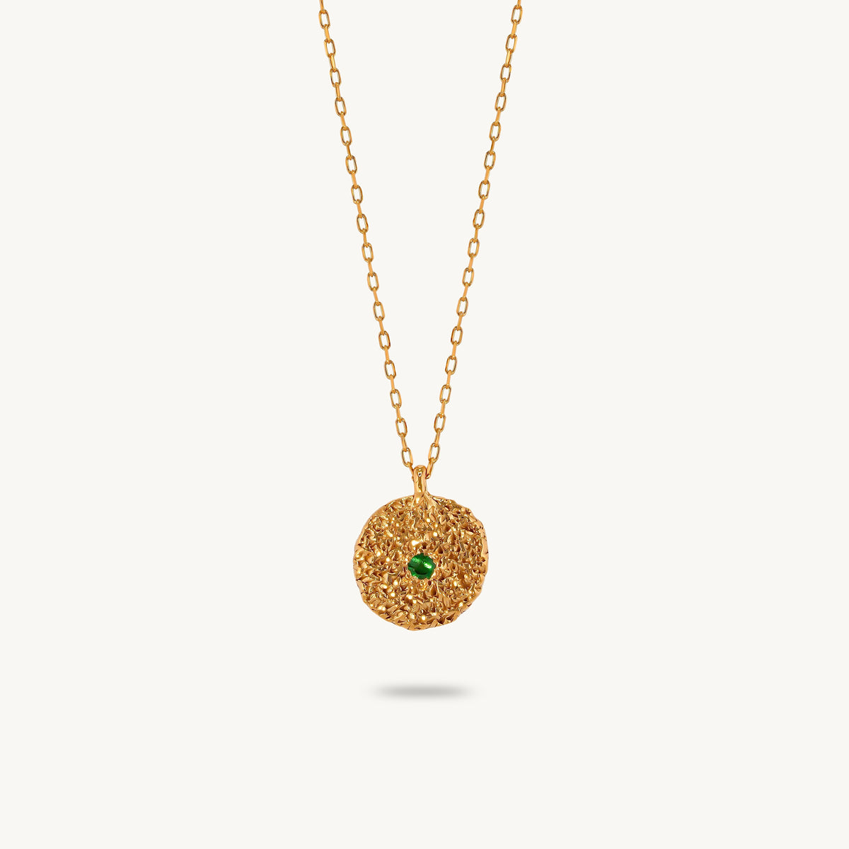 Gold-plated sterling silver chain necklace featuring a round, textured disc pendant with a small emerald set in the center.