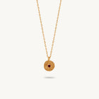 Gold-plated silver chain necklace featuring a round, textured disc pendant with a small red sapphire set in the center.