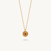 Gold-plated silver chain necklace featuring a round, textured disc pendant with a small red sapphire set in the center.