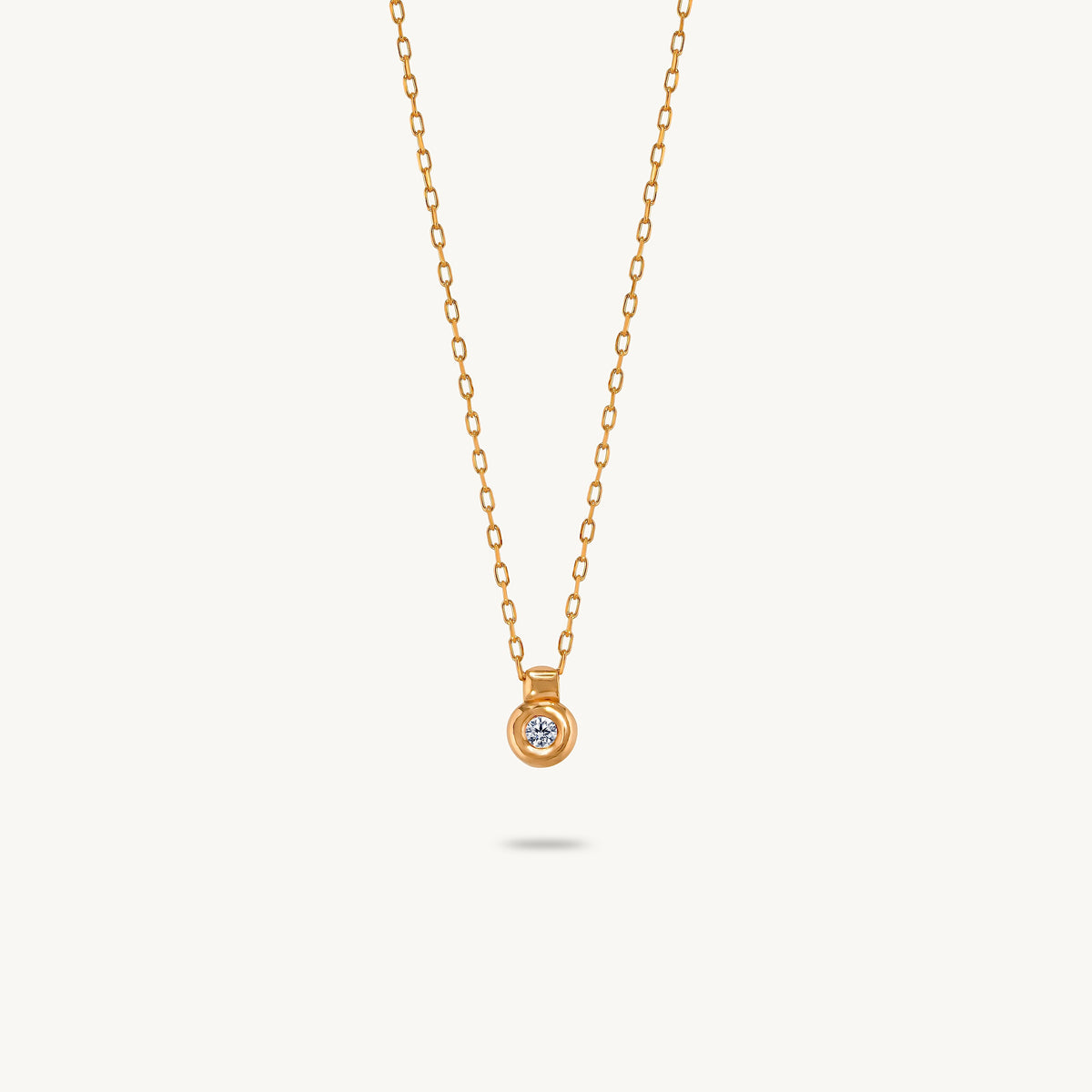 A gold-plated silver pendant featuring a smooth, sculptural bezel framing a single central white sapphire.